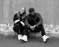 a black and white photo of a man and woman sitting next to a wall